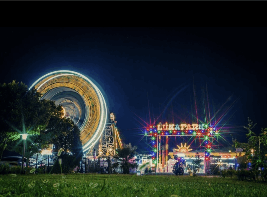 Gece uzun pozlamada dönen dönme dolap ve lunapark ışıkları